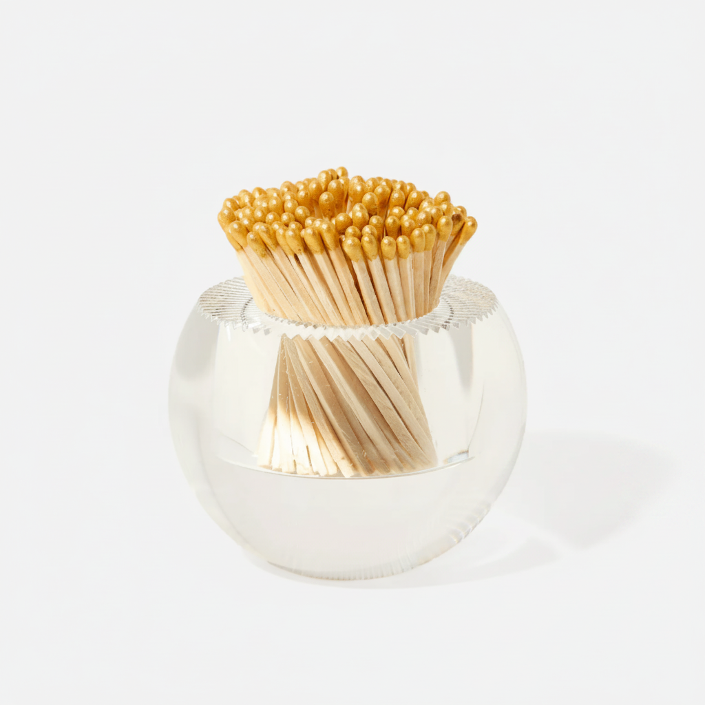 Clear glass container with gold matchsticks on a white background