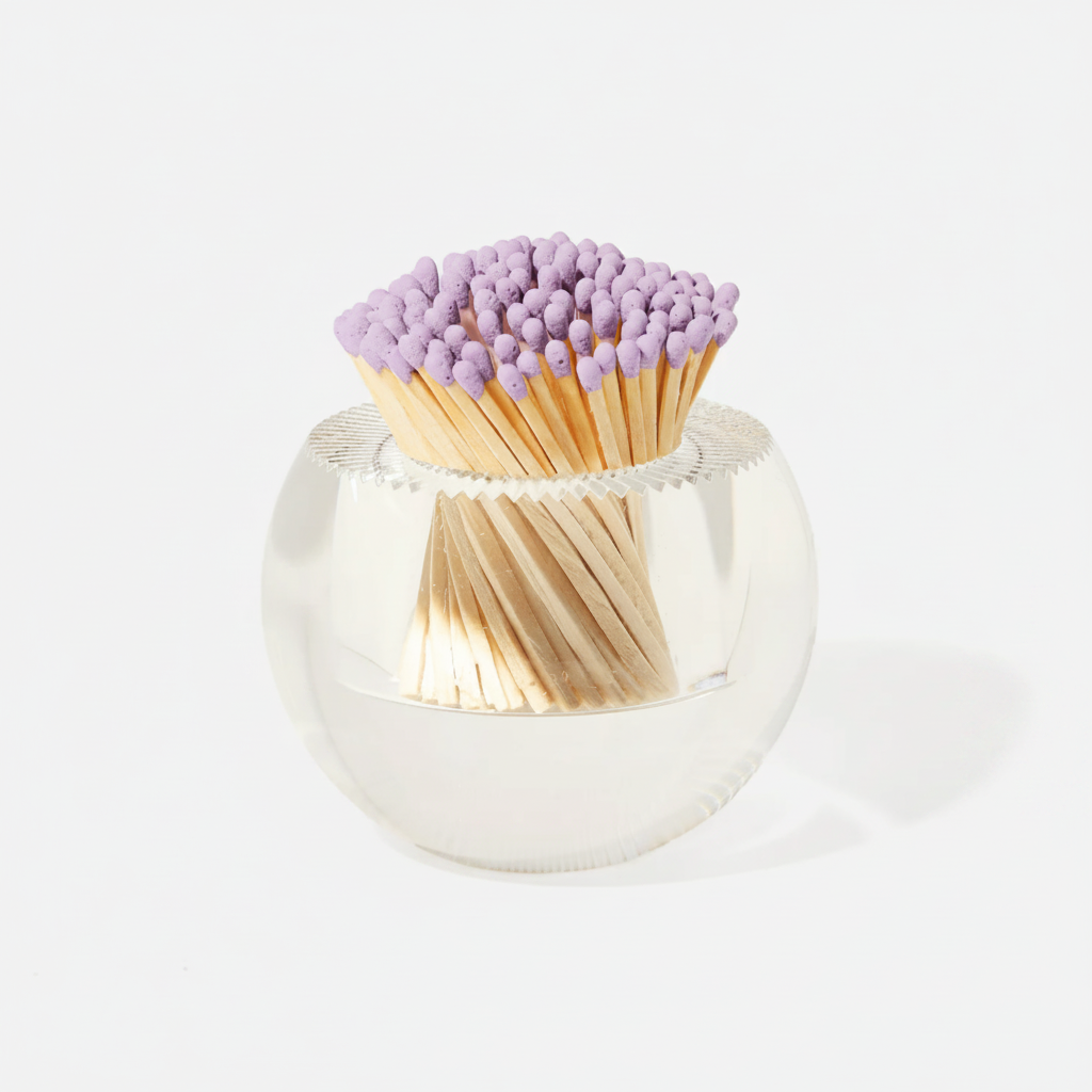 Matches with purple tips in a clear glass holder on a white background